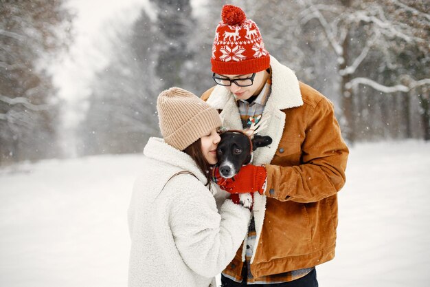 Teen boy and girl with their cute black dog standing at winter park