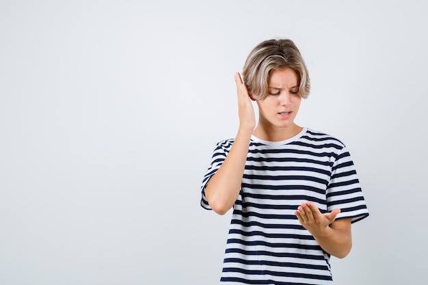 Teen boy looking at palm in t-shirt and looking curious . front view.