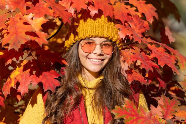 Teen child girl on autumn fall leaves background smiling girl in sunglasses at autumn leaves on natural background