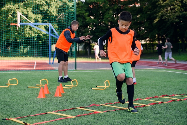 Teen football player running ladder drills on the turf during soccer training