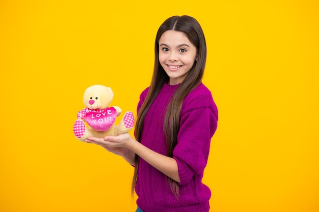 Teen girl in casual clothes hold soft toy for birthday on yellow background Kid spending time with her toys