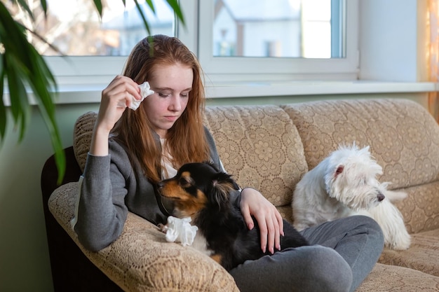 Teen girl crying in an embrace with a dog at home on the couch