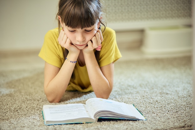 Teen girl doing homework sitting on the carpet in her room