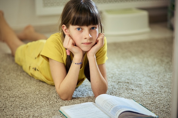 Teen girl doing homework sitting on the carpet in her room