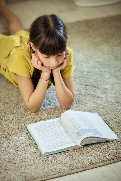 Teen girl doing homework sitting on the carpet