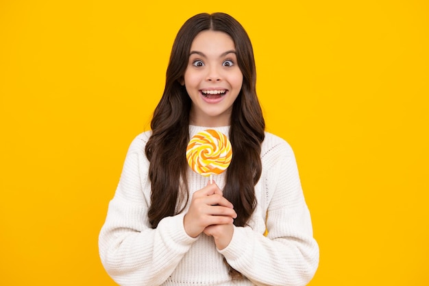 Teen girl hold lollipop caramel on yellow background candy shop Teenager with sweets suckers Happy face positive and smiling emotions of teenager girl