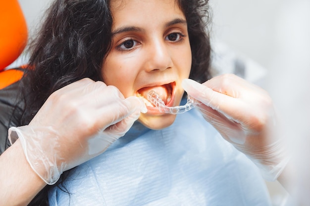 Teen girl holding braces dentist puts braces on girl dental care and orthodontic concept