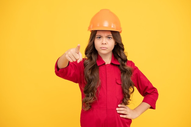 Photo teen girl pointing finger child in protective helmet for building protection and safety kid education concept on construction site improve your childhood future engineer making repairs