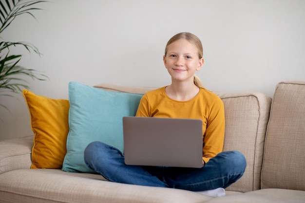 Teen girl sitting on couch with laptop