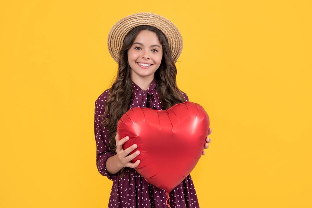 Teen girl smile with red heart balloon on yellow background