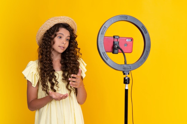 Teen girl speaking in front of camera for vlog isolated on yellow background Teenager working as blogger recording video blog