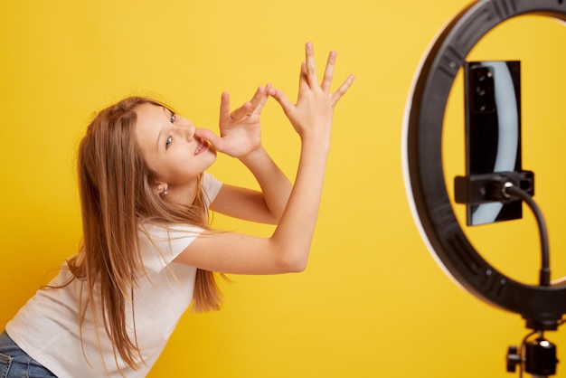 Teen girl speaking in front of camera for vlog isolated on yellow background teenager working as