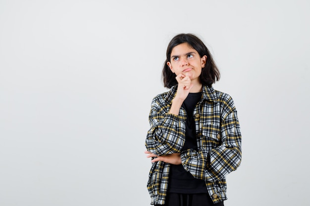 Teen girl standing in thinking pose, looking away in casual shirt and looking thoughtful. front view.