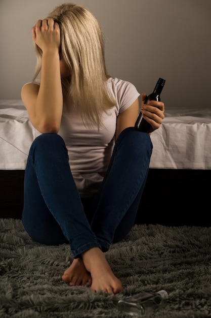 Teen girl suffering from a hangover while sitting on the floor