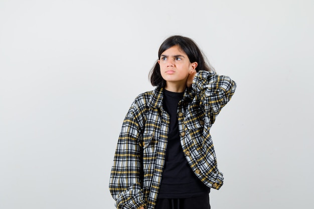 Teen girl suffering from neck pain, looking away in casual shirt and looking unwell. front view.