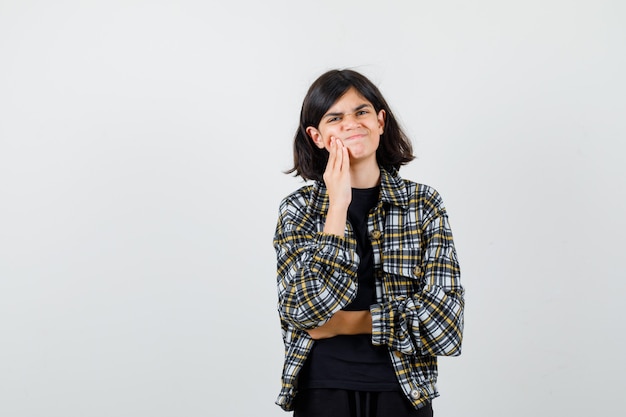 Teen girl suffering from toothache in casual shirt and looking painful. front view.