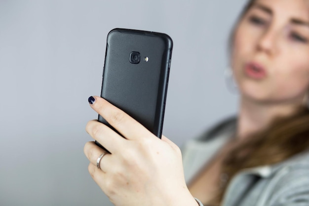 Teen girl taking selfie with duckface with her mobile phone