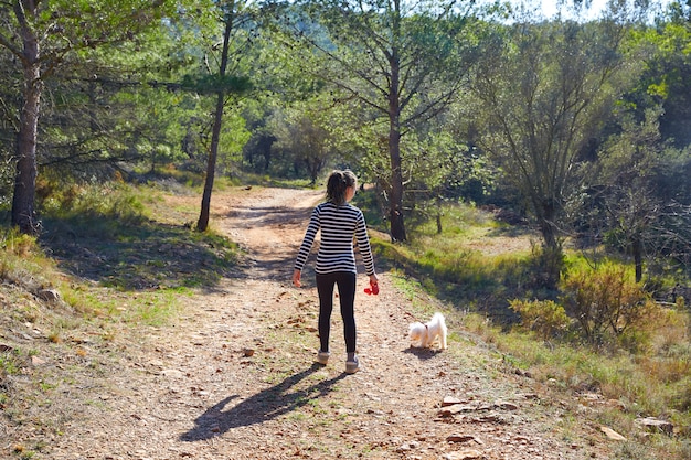 Teen girl walking with a white dog in forest