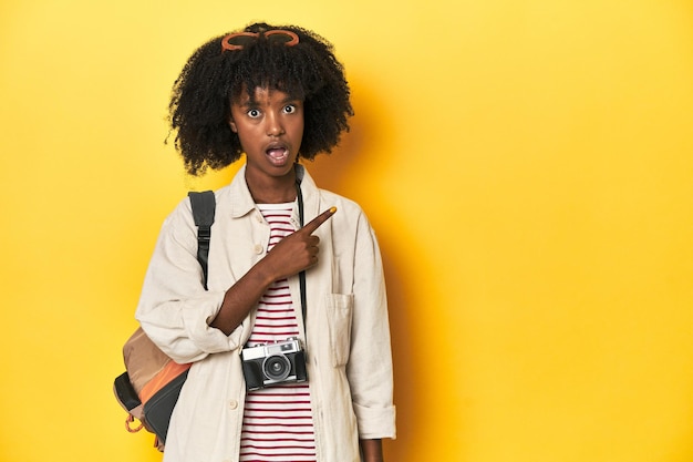 Teen girl with backpack camera ready for vacation pointing to the side