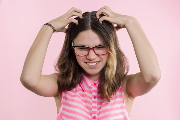 Teen girl with glasses, with long hair scratches her head