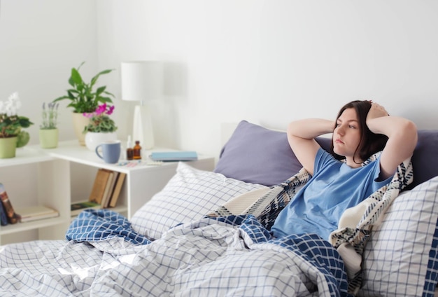 Teen girl with headache on bed in white room