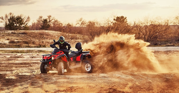 Photo teen riding atv in sand dunes making a turn in the sand