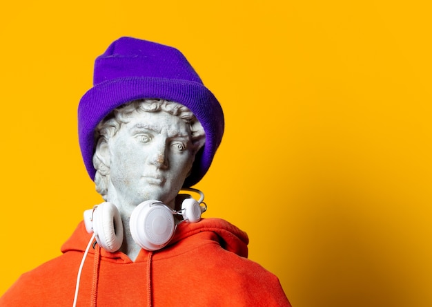 Teen sculpture in orange hoodie and headphones on yellow background