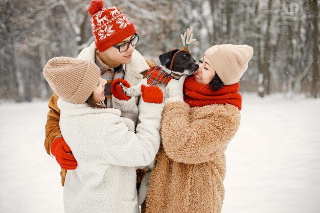 Teen siblings their mother and black dog standing at winter park