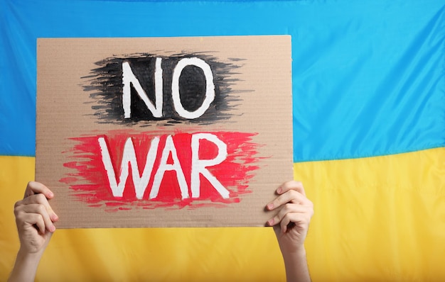 Teenage boy holding poster No War against Ukrainian flag closeup Space for text