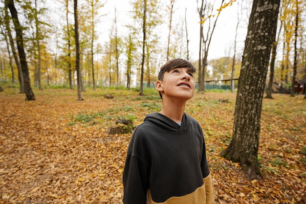 Teenage boy looking above in autumn forest