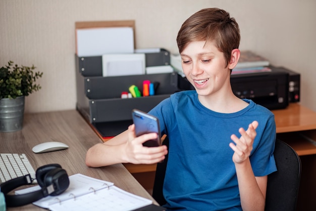 A teenage boy makes a video call using his mobile phone to his friends, classmates, and relatives.