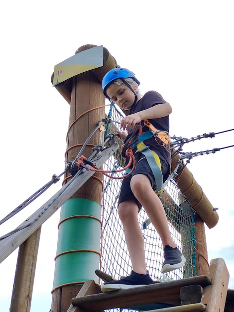 A teenage boy moves on wooden stairs in a rope amusement park Active youth sports recreation