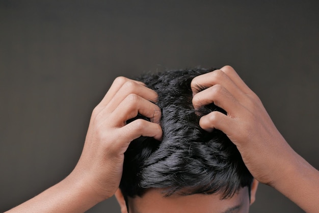 Teenage boy Scratching Head Against black background