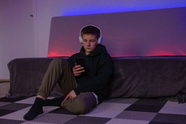 Teenage boy using phone in his room with neon light