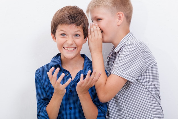 Photo teenage boy whispering in the ear a secret to friendl on white background