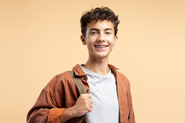 teenage boy with dental braces isolated on beige background closeup Education concept