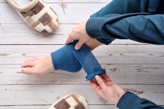 Teenage boy wrapping compression bandage around sprained ankle Ankle Medical Support Strap crutches