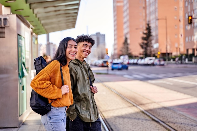 Teenage couple waiting at the train or tram stop young students with a guitar and a ukulele in its case