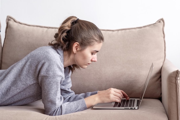 A teenage female student is working on a laptop at home