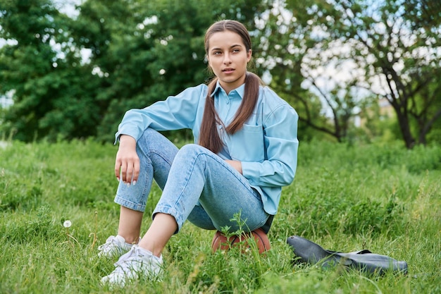 Teenage female student sitting on the grass on a basketball ball