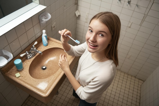 Photo teenage girl brushing teeth in bathroom mirror