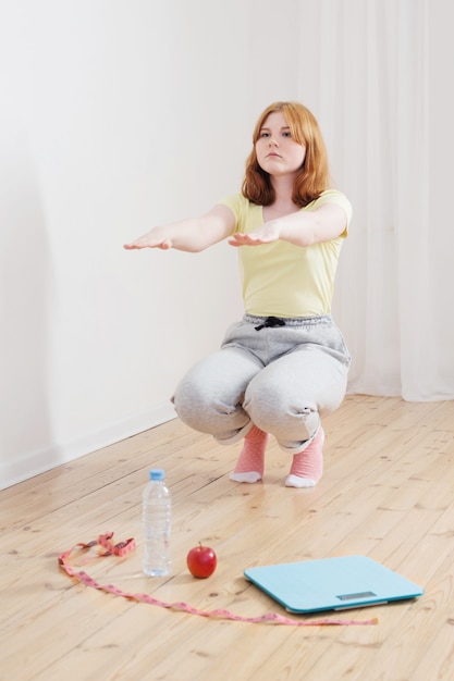 Teenage girl doing sports at home, electronic scales on the floor