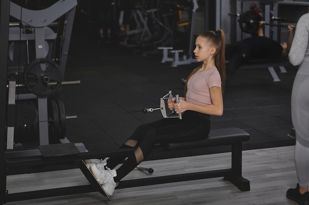 Teenage girl exercising on rowing gym machine copy space