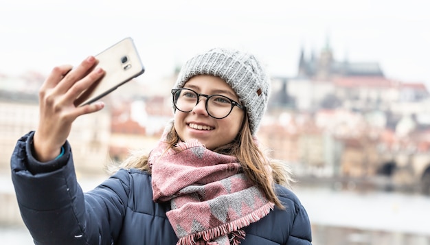 Teenage girl in glasses takes a selfie in Prague on a cold winter day.