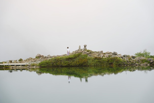 Teenage girl happy traveler looking the mist in mountains with lake people with landscape