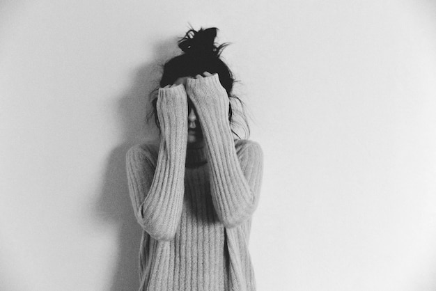 Photo teenage girl hiding face while standing against white background