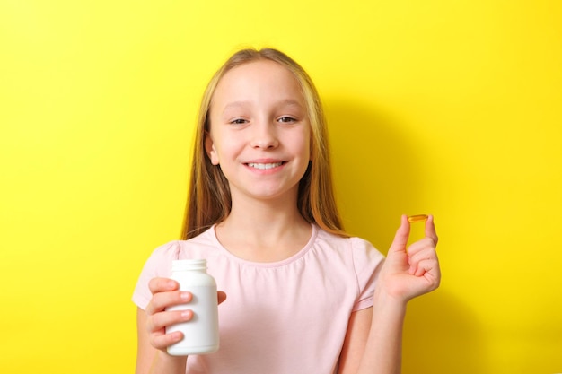 A teenage girl holds an omega 3 capsule in her hands on a colored background Fish oil natural supplements High quality photo