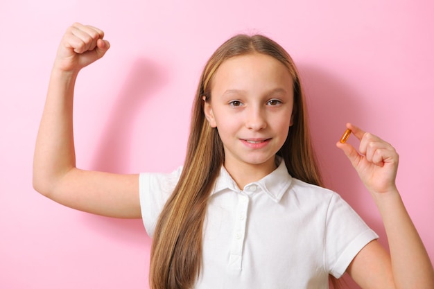 A teenage girl holds an omega  capsule in her hands on a colored background