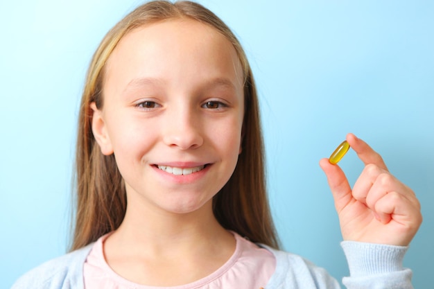 A teenage girl holds an omega capsule in her hands on a colored background