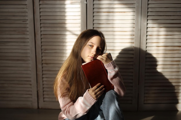 A teenage girl is sitting on the floor with a book Problems of teenagers